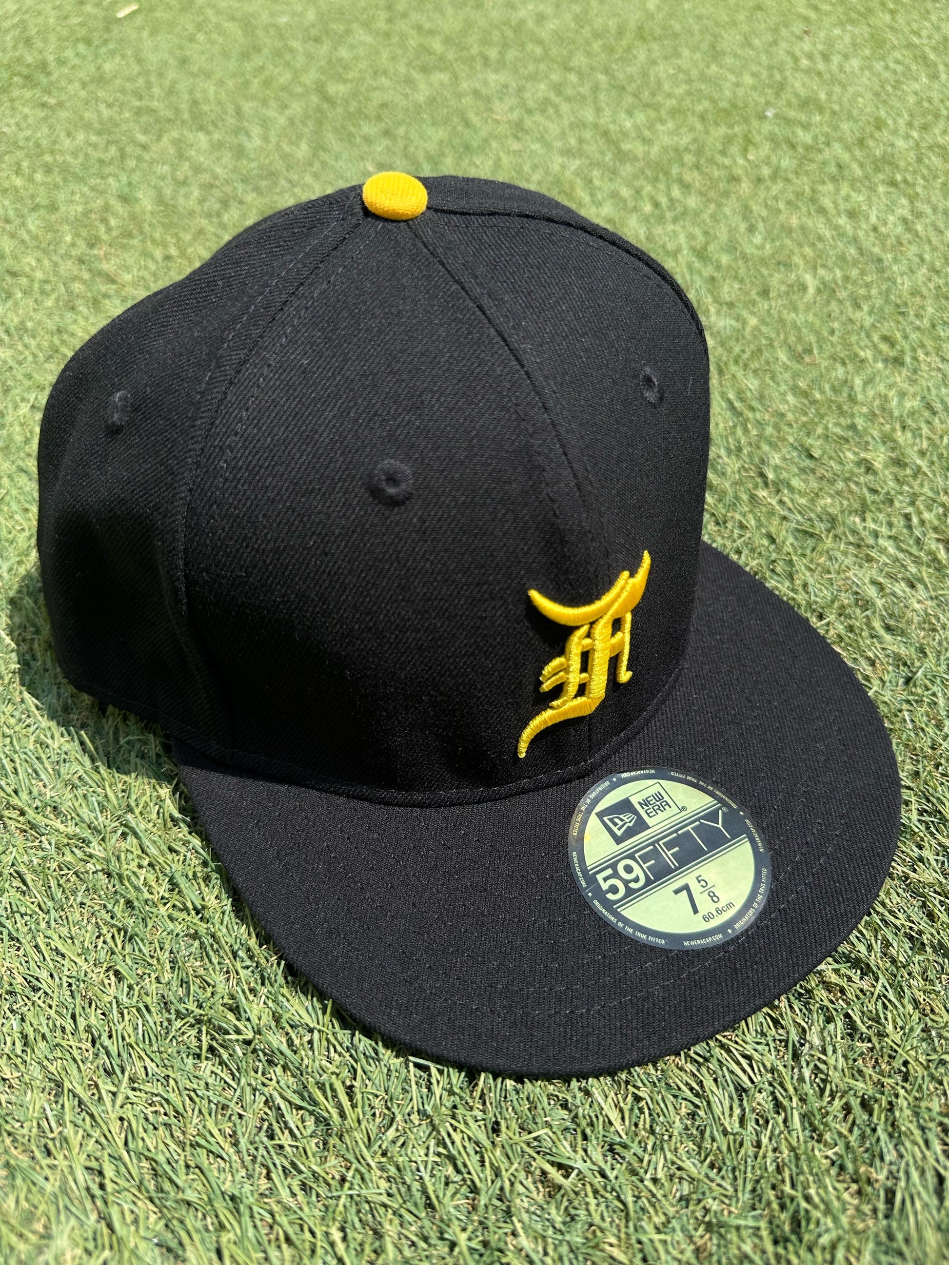 "Gorra New Era 59FIFTY Fear Of God Essentials amarilla con visera plana y diseño minimalista."